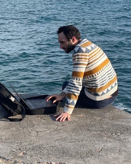 Pablo Fiorentini working on a laptop by the sea